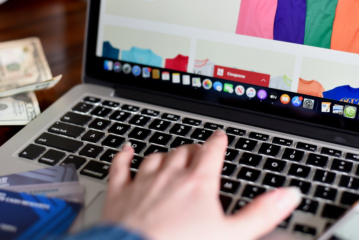 Hand typing on a silver laptop keyboard during online shopping.