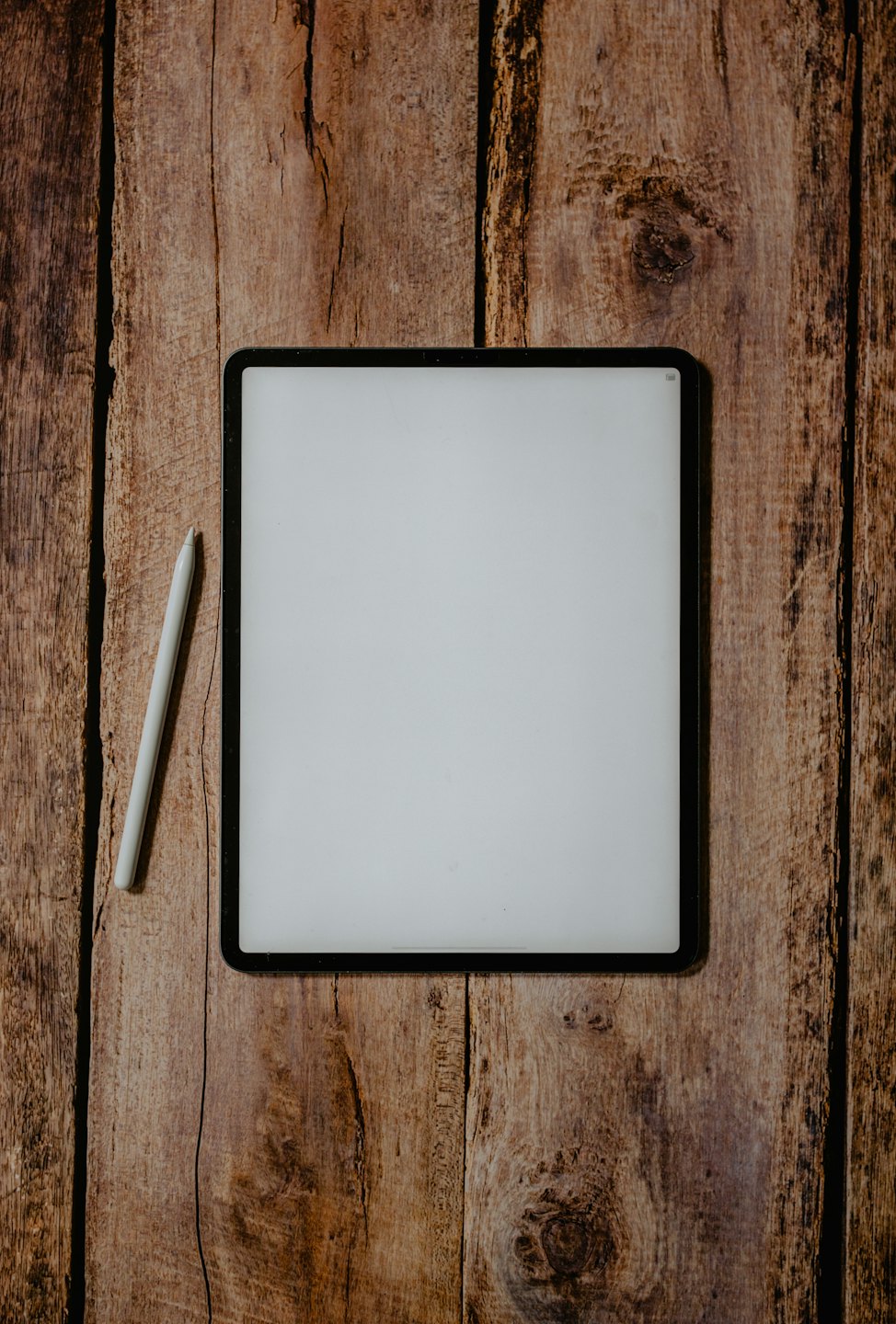 A digital tablet and stylus on a wooden table.