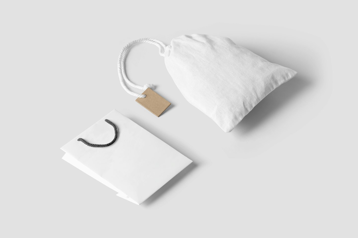 White shopping bag and drawstring pouch on grey surface.